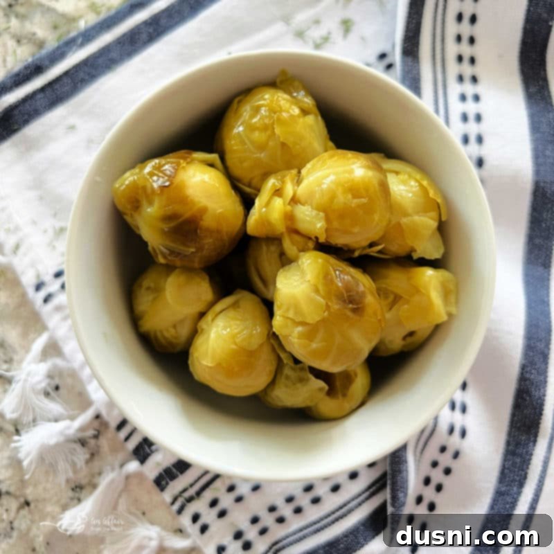 Creamy Dill & Brussels Sprout Dip 5 Dilled Brussels Sprouts Dip in a white bowl with crackers and carrot sticks around it