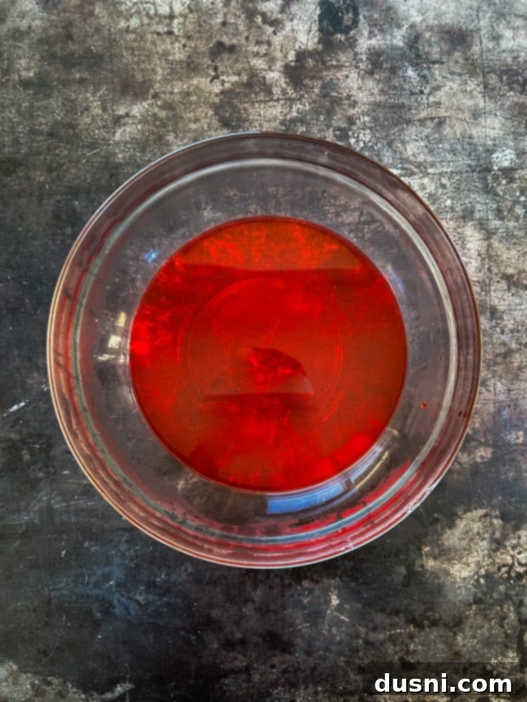 Holiday Cherry Pie Bliss 6 The initial step of mixing Jell-O powder with boiling water in a large bowl.