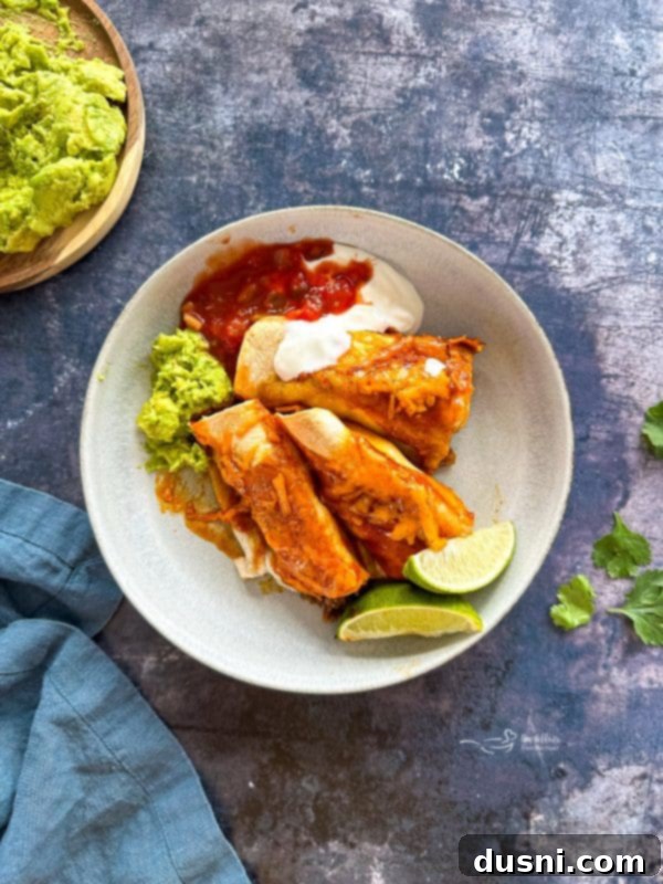 Quick & Easy Ground Beef Enchiladas 2 Close-up of a baking dish filled with Easy Ground Beef Enchiladas, topped with melted cheese and fresh cilantro.
