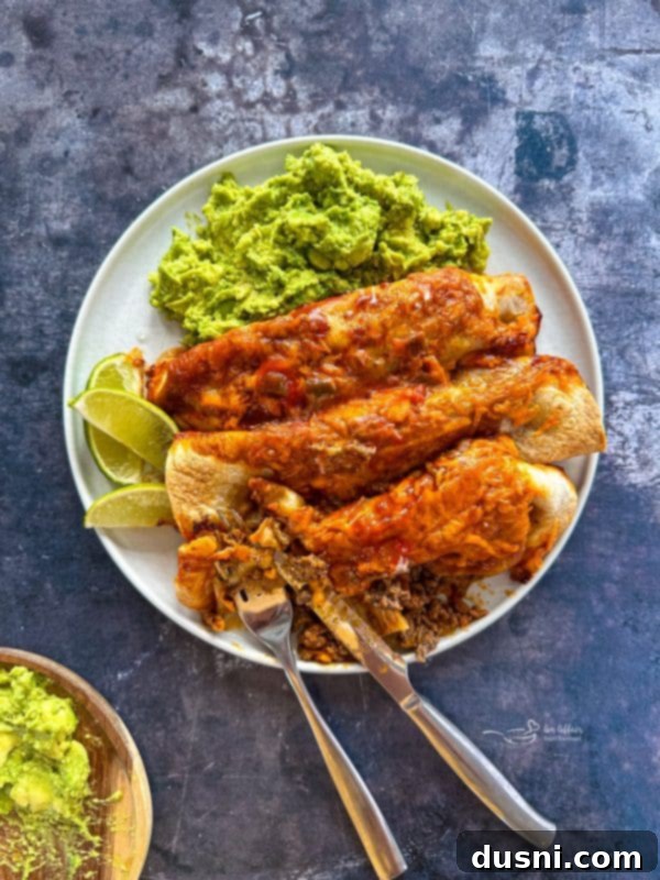 Quick & Easy Ground Beef Enchiladas 11 A cooked enchilada on a cutting board, garnished with fresh cilantro.