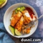 Quick & Easy Ground Beef Enchiladas 15 Fork cutting into a baked enchilada topped with cheese and cilantro, served from the baking dish.