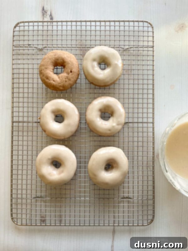 A bowl of creamy vanilla cinnamon glaze for dipping donuts, with a whisk resting in it.