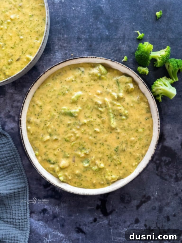 A steaming bowl of creamy homemade broccoli cheese soup garnished with fresh parsley.