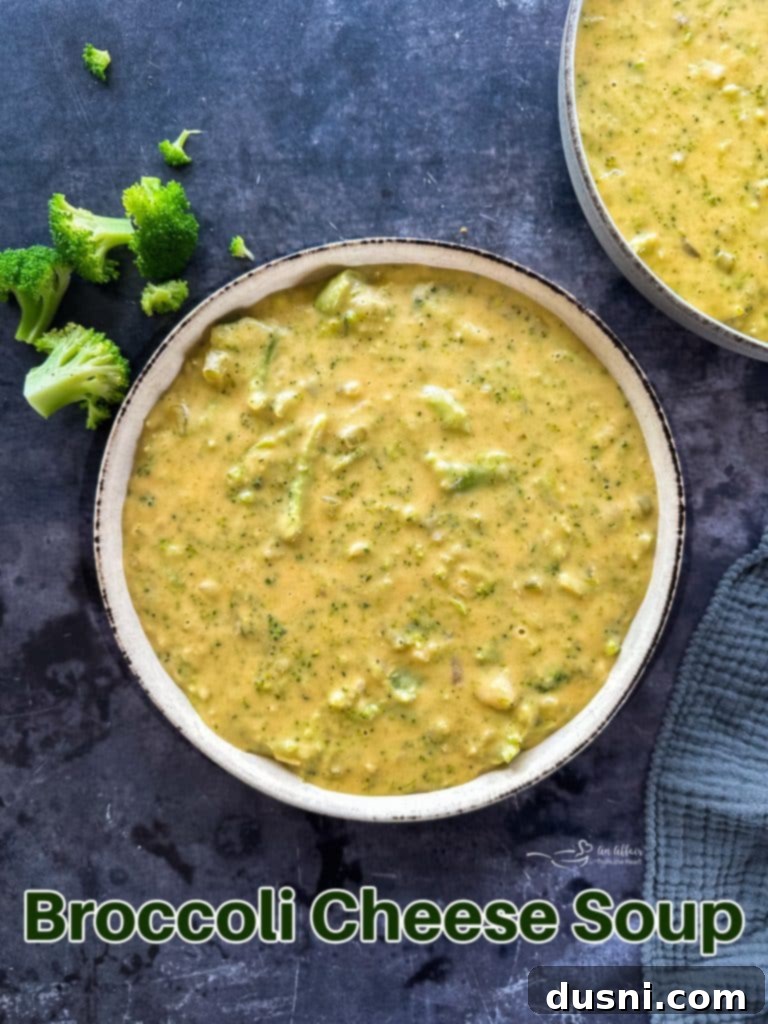 A large bowl of creamy broccoli cheese soup with a spoon, ready to be eaten.