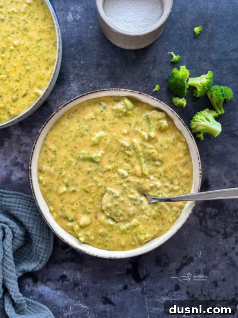 A large pot of creamy broccoli cheese soup simmering on the stovetop.