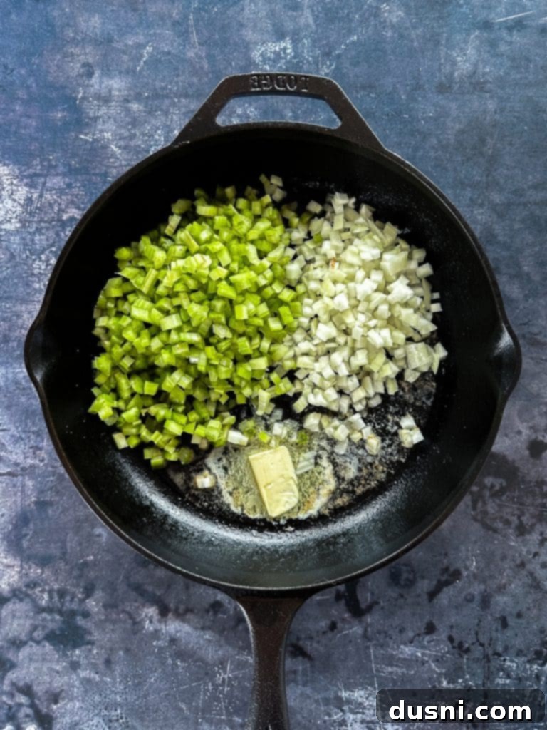 Chopped onions and celery sautéing in butter in a large pot on the stove.