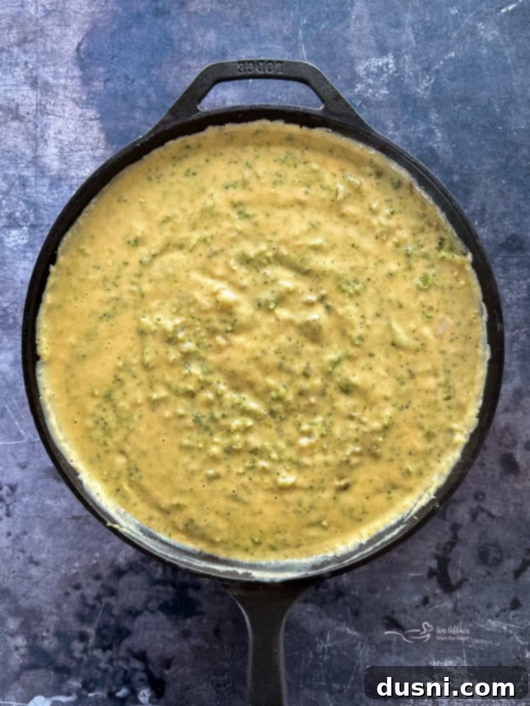 A bowl of creamy broccoli cheese soup topped with a dollop of sour cream.