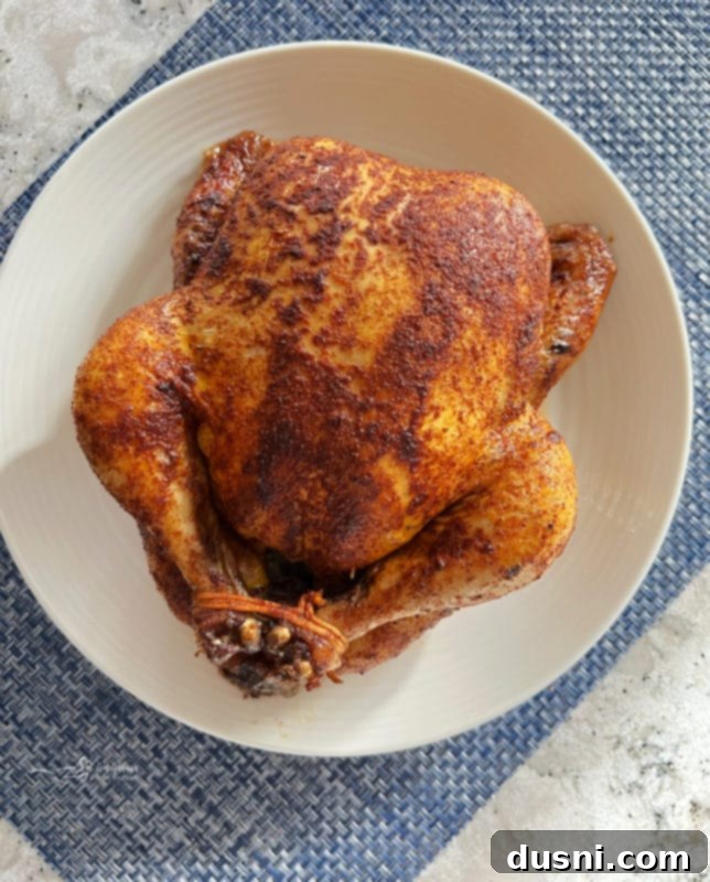 Carved Slow Cooker Rotisserie Chicken on a serving platter with herbs