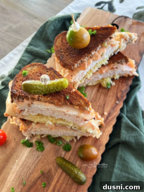 A perfectly grilled Turkey Reuben sandwich, sliced in half, revealing layers of turkey, melted Swiss cheese, sauerkraut, and Thousand Island dressing between marbled rye bread.