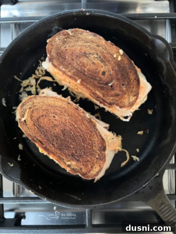 Grilling a Turkey Reuben sandwich in a hot skillet, with butter sizzling.