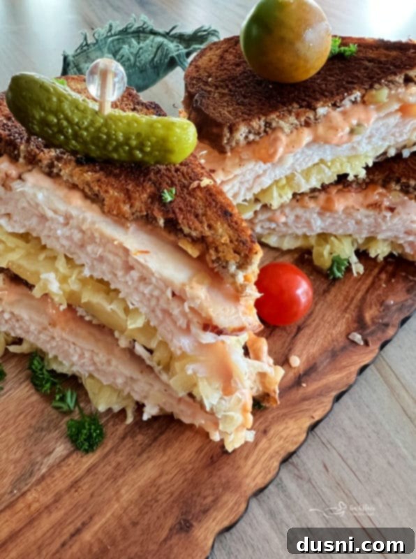 Close-up of a half Turkey Reuben sandwich, showcasing the grilled marbled rye, generous layers of turkey, Swiss cheese, and sauerkraut.