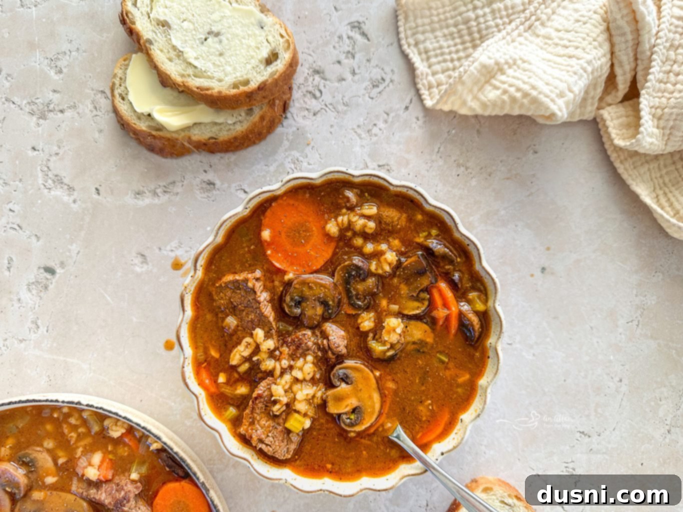 Hearty Beef and Mushroom Barley Soup 3 Overhead shot of a bowl of rich Vegetable Beef Barley Soup, with visible chunks of beef, mushrooms, and barley.