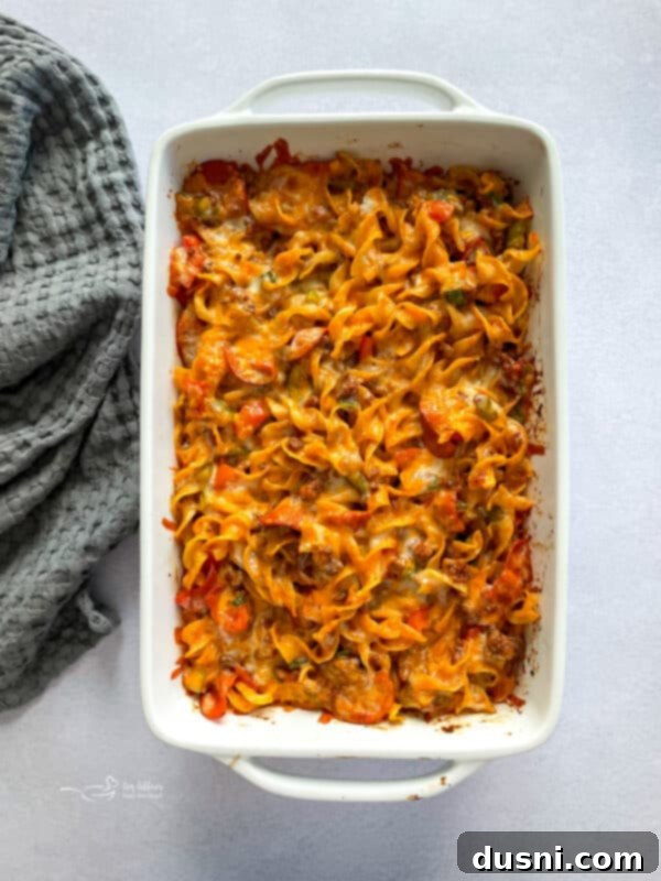 Pizza pasta casserole topped with cheese, ready for baking