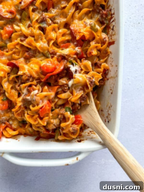 A dish of pizza pasta before baking, showing the layers of ingredients