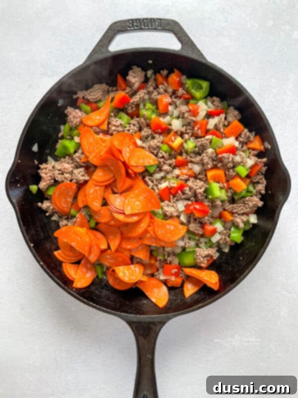 Ground beef and vegetables browning in a skillet for pizza pasta