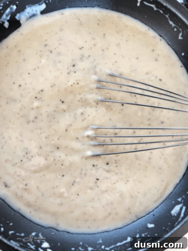 Finished white country gravy in a skillet, perfectly creamy and ready to serve.