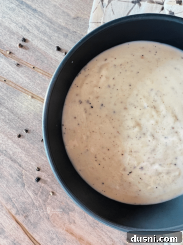 A close-up shot of a plate of biscuits smothered in white country gravy.