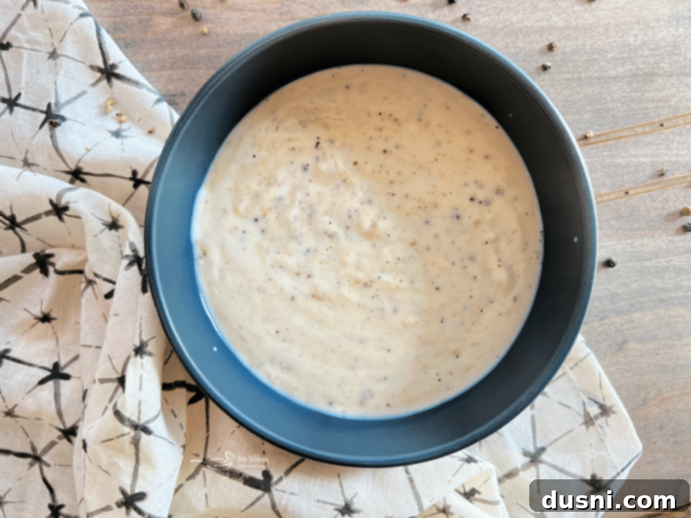 Close-up of a skillet filled with freshly made white country gravy, showing its creamy texture.
