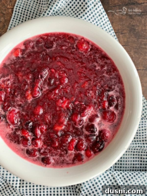 Mom's Homemade Cranberry Perfection 8 Homemade cranberry sauce just removed from the stove, cooling in a bowl before thickening, showcasing its initial liquid consistency.