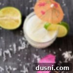 Overhead view of a Mini Vacation - aka Brazilian Lemonade Cocktail, garnished with lime and a cocktail umbrella.