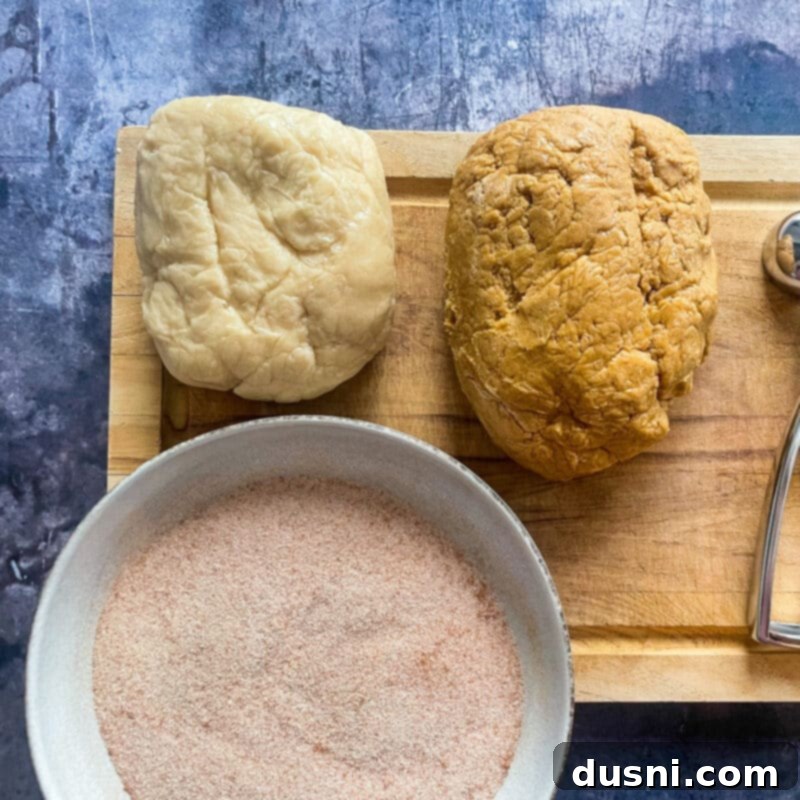 Formed Gingerdoodle cookie dough balls coated in cinnamon sugar, ready for baking on a parchment-lined sheet.