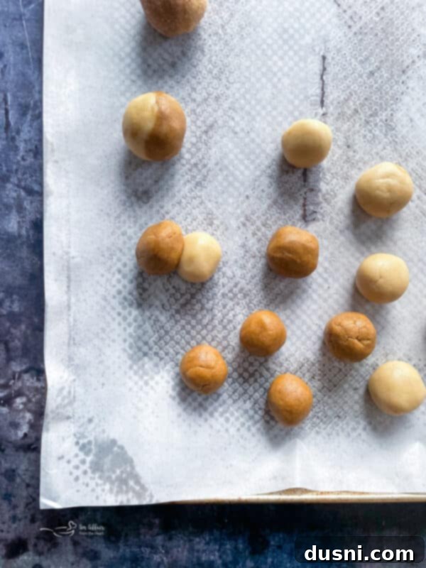 Hands rolling a combined ball of Snickerdoodle and Gingersnap dough into a sphere.