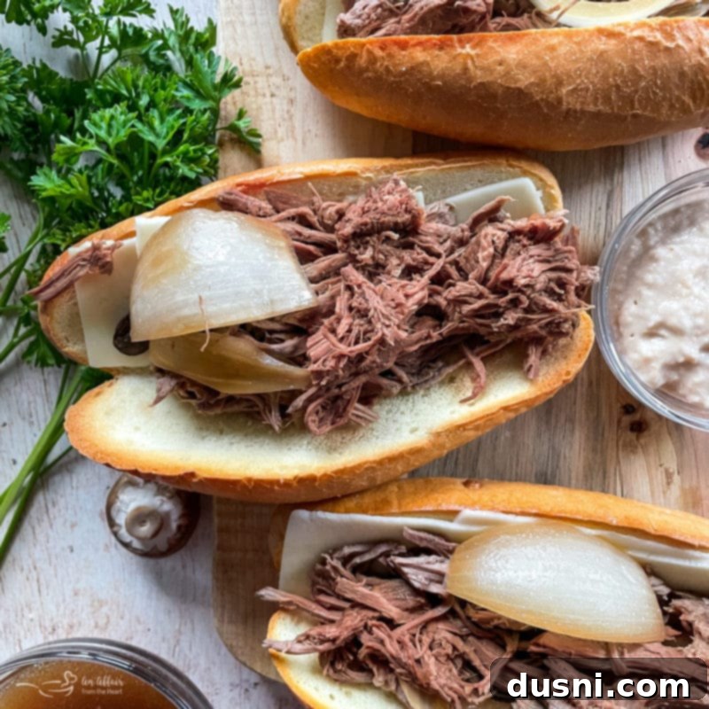 Mouthwatering Crock Pot French Dip Sandwiches 11 Assembled French dip sandwich, loaded with beef and cheese, ready for dipping.