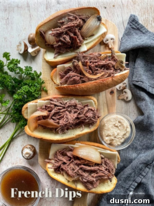 Mouthwatering Crock Pot French Dip Sandwiches 14 French dips on a cutting board with a side of au jus, ready to be served.