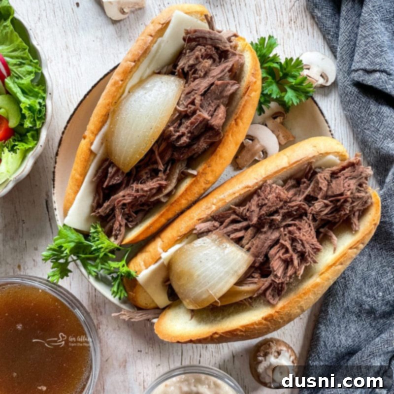Mouthwatering Crock Pot French Dip Sandwiches 4 Close-up of two French onion French dip sandwiches with visible onions, highlighting the delicious filling.