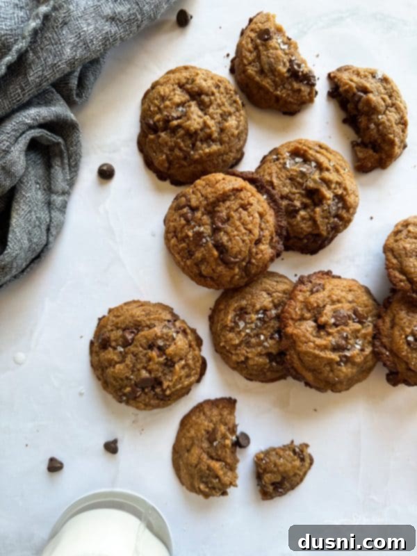 Close-up of baked Malted Chocolate Chip Cookies on a cooling rack, showing their crinkled tops and generous chocolate distribution.