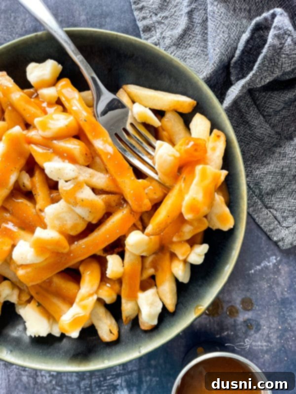 Authentic Homemade Poutine: A Canadian Classic 2 Canadian Poutine in a bowl with fork
