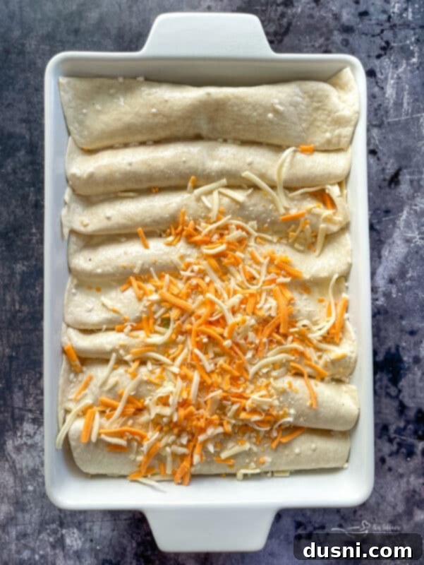 Raw egg custard mixture poured over rolled enchiladas in a baking dish, ready for refrigeration