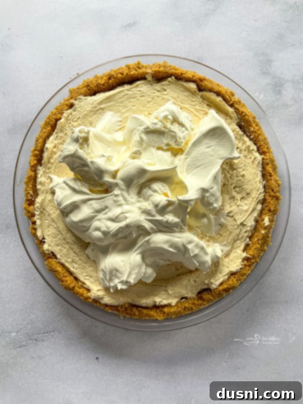 The smooth peanut butter filling being spread evenly into the pre-chilled graham cracker crust