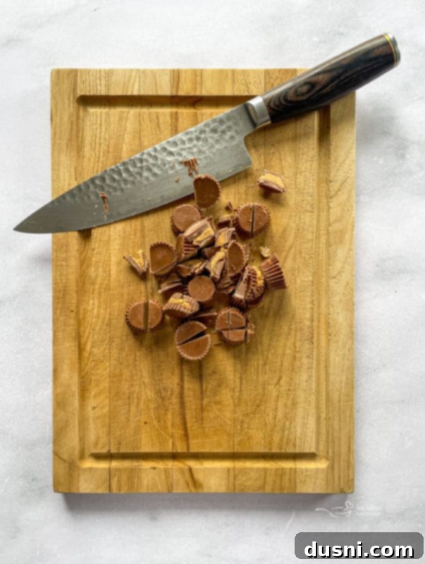 Close-up of Reese's Peanut Butter Cups being roughly chopped on a cutting board, ready for the pie topping