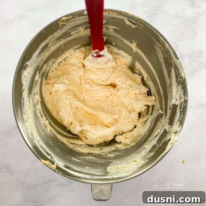 A bowl containing cream cheese, powdered sugar, and peanut butter being mixed until smooth for the pie filling