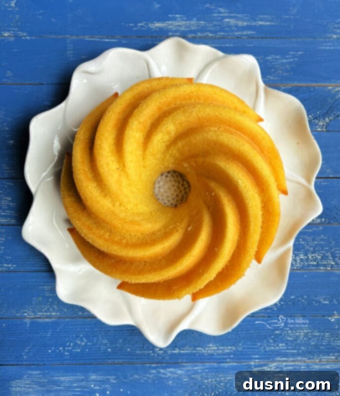 Luscious Lemon Cream Cheese Bundt Cake 11 A freshly baked golden lemon bundt cake without frosting, cooling on a rack