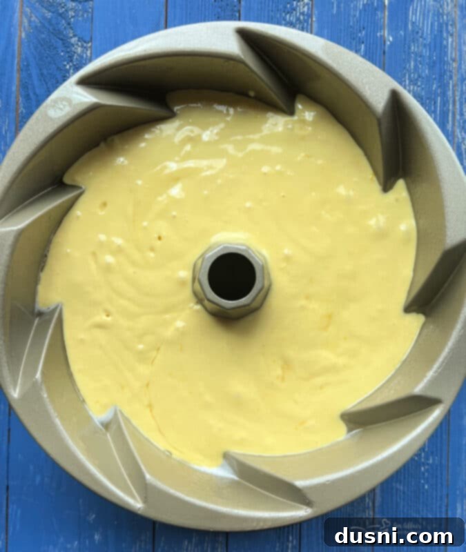Luscious Lemon Cream Cheese Bundt Cake 10 Pouring lemon bundt cake batter into a prepared bundt pan