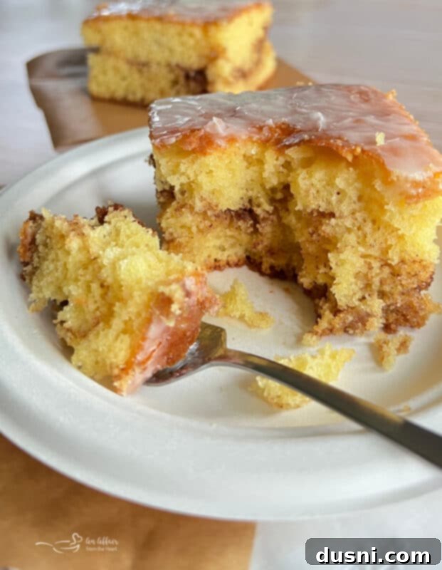 Honey Bun Cake on a Plate with a Fork, showing the moist texture and cinnamon swirl