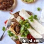 Tender Slow Cooker Pulled Beef Burritos 14 A shredded beef burrito opened so you can see the inside, showing the tender beef filling.