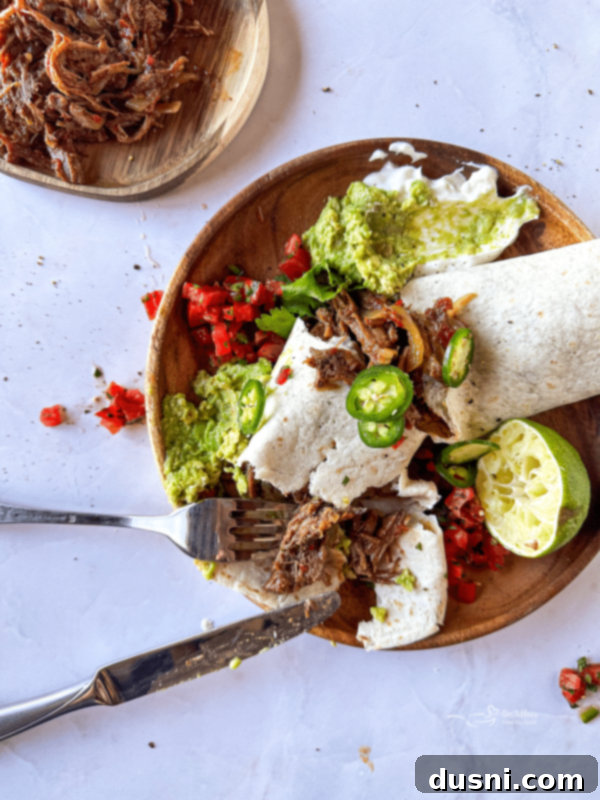 Tender Slow Cooker Pulled Beef Burritos 3 Close up of a freshly made shredded beef burrito, perfectly wrapped in a warm flour tortilla.