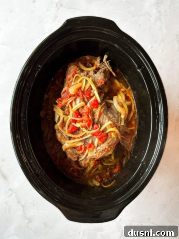 Tender Slow Cooker Pulled Beef Burritos 7 Shredded beef in a slow cooker after cooking, perfectly tender and coated in sauce.