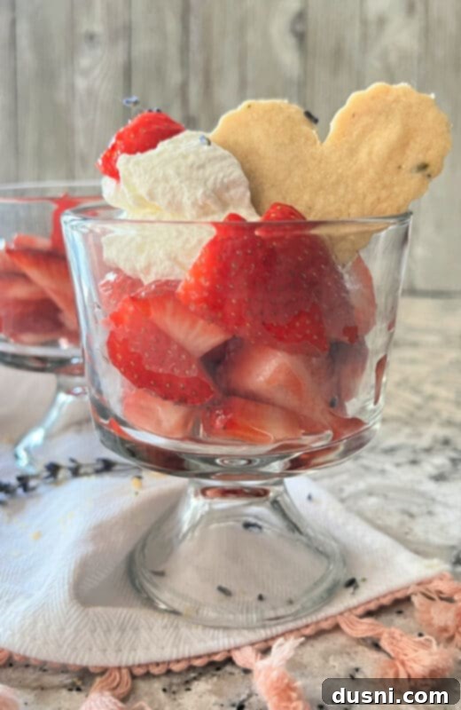 Lavender Shortbread and Lavender Strawberry Cream 6 Several neatly stacked lavender shortbread cookies with a bowl of lavender-infused strawberries and whipped cream in the background, all on a rustic wooden surface.