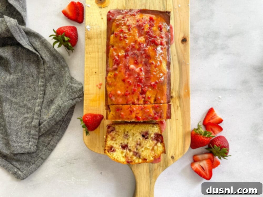 Close-up of a freshly baked strawberry bread loaf, showcasing its tender crumb and glistening glaze.