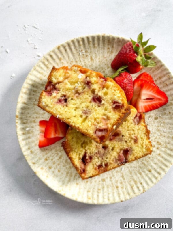 Two slices of Glazed Strawberry Bread on a white plate, ready to be served.
