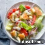 Little King Salad on a scalloped plate, glistening with dressing.