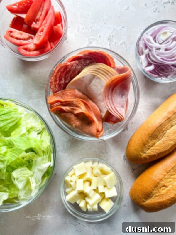 A vibrant display of chopped ingredients for Little King Salad: lettuce, tomatoes, red onion, deli meats, and provolone cheese.