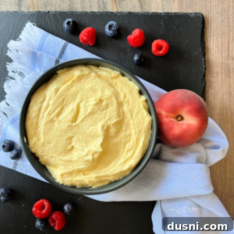 Step five: The finished creamy vanilla almond fruit dip in a bowl, surrounded by fresh fruit for dipping, including strawberries, grapes, and apple slices.