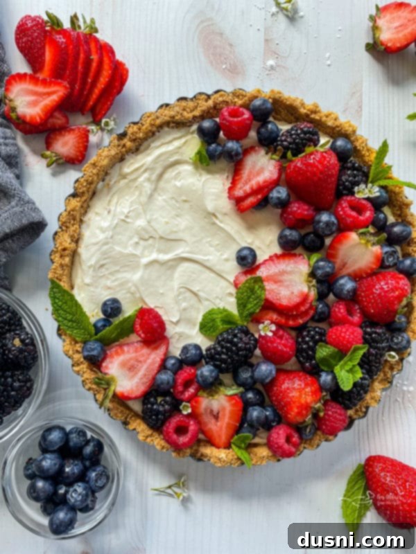 Top view of a stunning no-bake fruit tart generously topped with fresh mixed berries and kiwi slices.