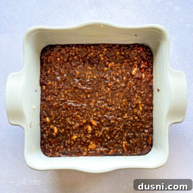 Mixing peanut butter, vanilla, oats, and peanuts into the chocolate mixture.