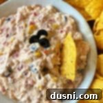 Easy 5 Ingredient Fiesta Corn Dip 16 Fiesta Corn Dip in a white bowl with tortilla chips around it, garnished with fresh cilantro